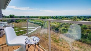 A balcony with a view of a grassy landscape and a clear sky.