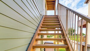 A wooden staircase with a railing leading to a deck area.