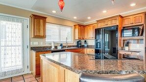A modern kitchen with wooden cabinets, granite countertops, a stainless steel refrigerator, and a built-in microwave.