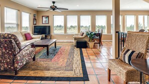 A spacious living room with a sofa, armchairs, a coffee table, and a TV.