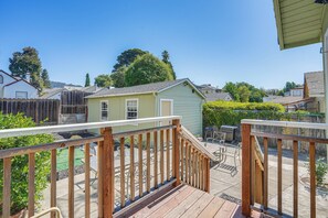 Une terrasse en bois avec une rambarde, un petit abri de jardin et un espace patio aménagé avec du mobilier d’extérieur.