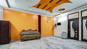 A room with a marble floor, an ornate sofa, a ceiling fan, and a clock on the wall. - Hotel Sunshine By The Premium Villa (New Delhi)