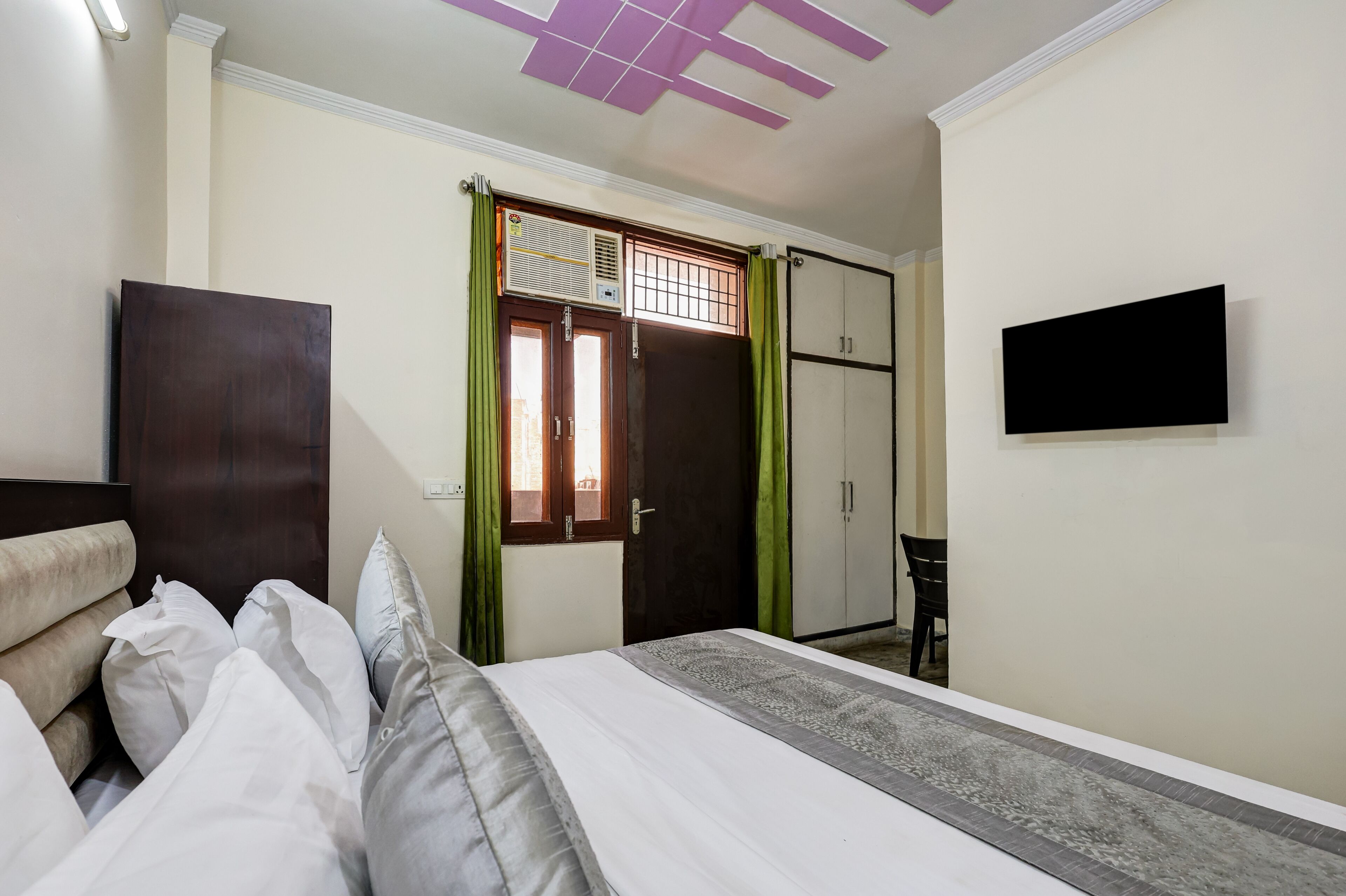 Ein Hotelzimmer mit Bett, Kleiderschrank, Schreibtisch und Fernseher an der Wand.
