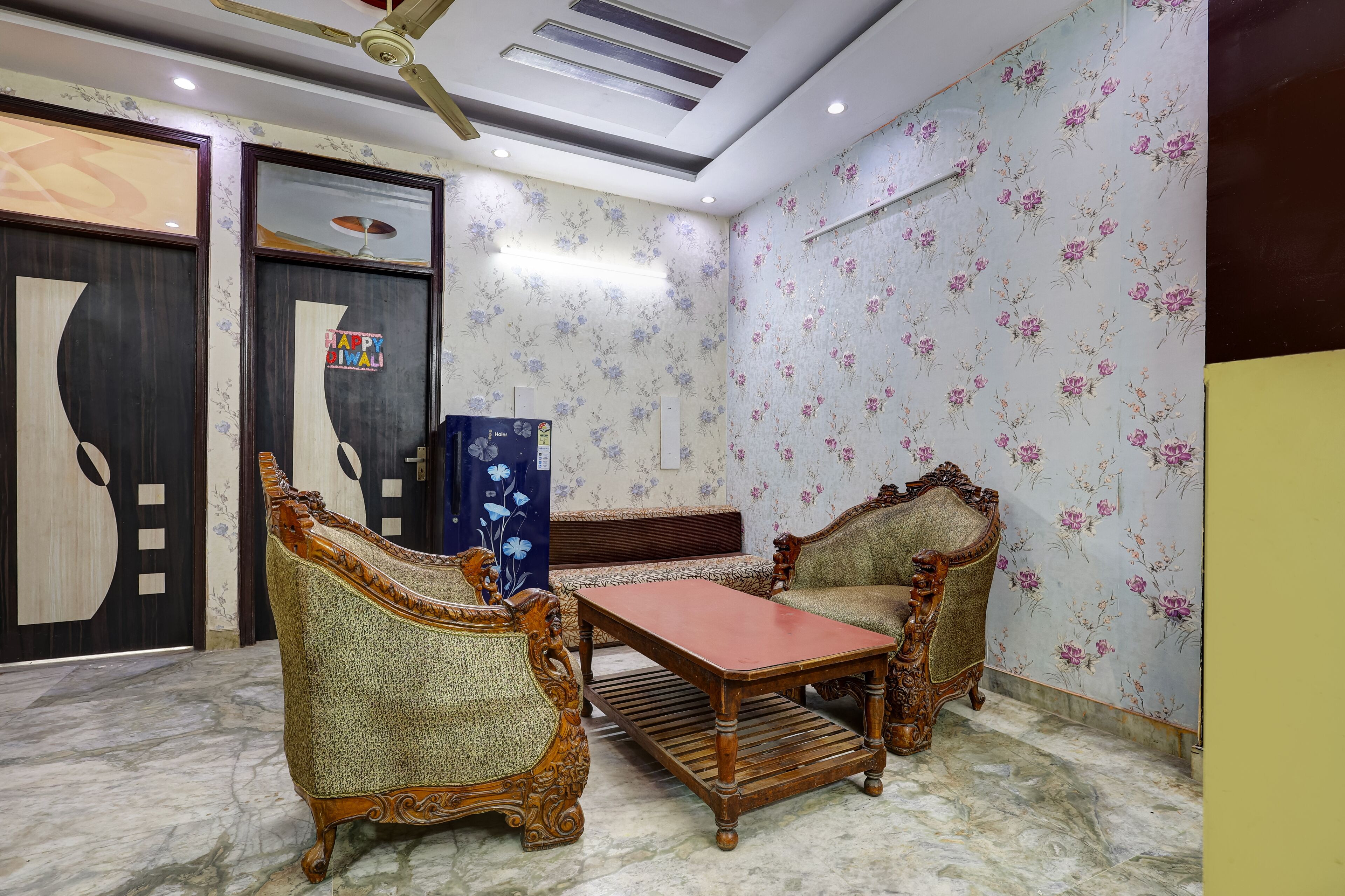 A room with a marble floor, floral wallpaper, a ceiling fan, a wooden table, and two ornate chairs.