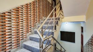 A staircase with a patterned brick wall, metal handrail, and a blackboard on the wall. - Hotel Sunshine By The Premium Villa (New Delhi)