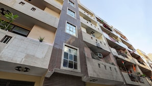 A multi-story residential building with balconies, windows, and some potted plants. - Hotel Sunshine By The Premium Villa (New Delhi)