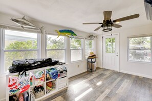 A spacious room with large windows, a ceiling fan, and a storage unit with folded clothes.