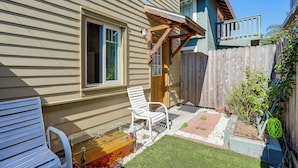 Ein Garten mit einer Holzterrasse, einem weißen Stuhl, einem Glastisch und einer kleinen Gartenanlage.
