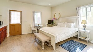 Ein Schlafzimmer mit einem Bett, einer Bank, einem Schreibtisch, einem Stuhl, einem Fernseher und einem Fenster mit Vorhängen.