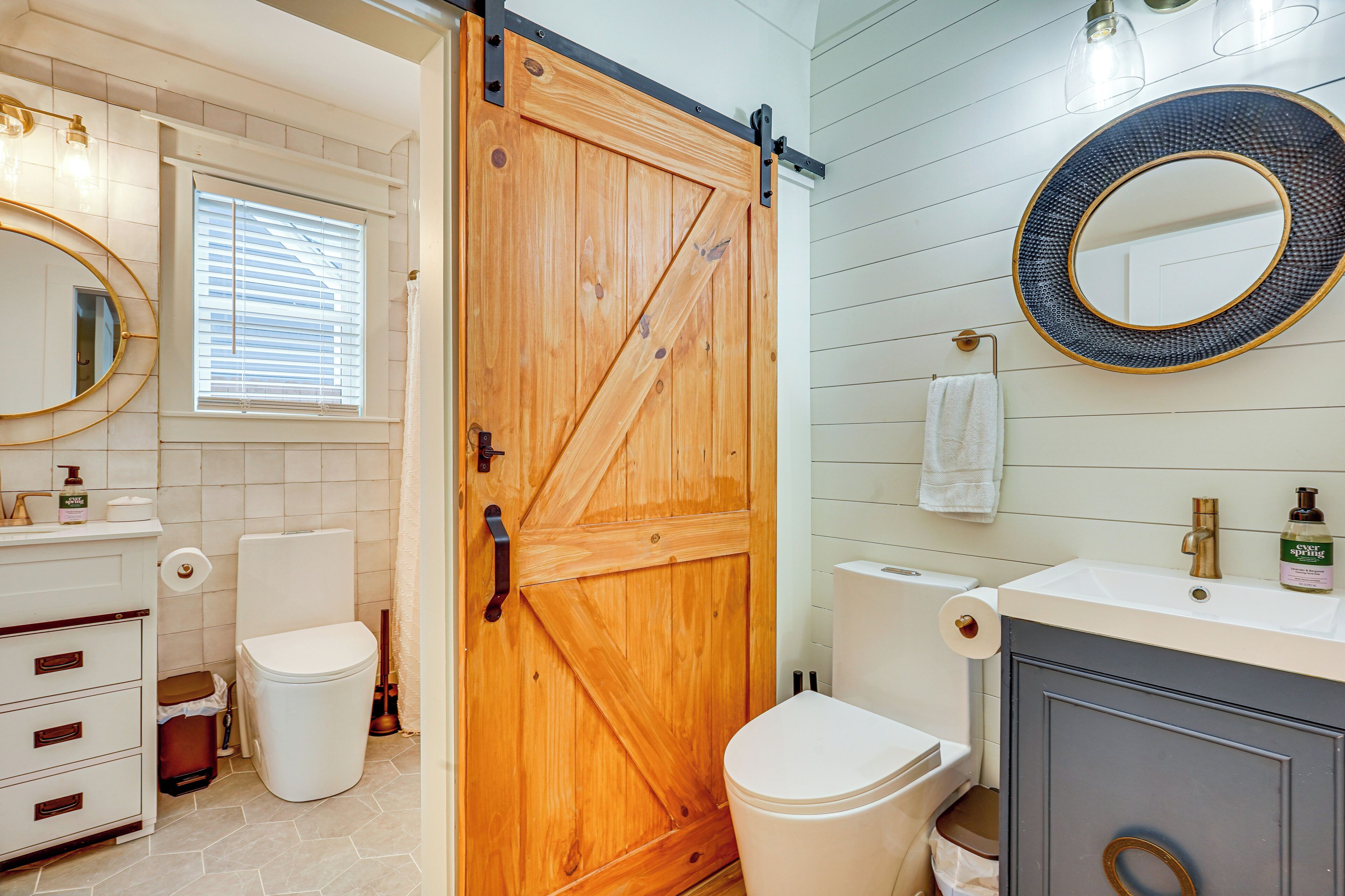 A bathroom with a wooden door, a white toilet, a sink with a mirror, and a towel hanging on the wall.