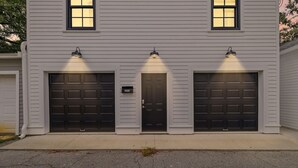 A two-story house with three garage doors, each with a light above it. - Pet-friendly Renovated Apt Steps to Forsyth, Coffee Shops by Lucky Savannah (Savannah)