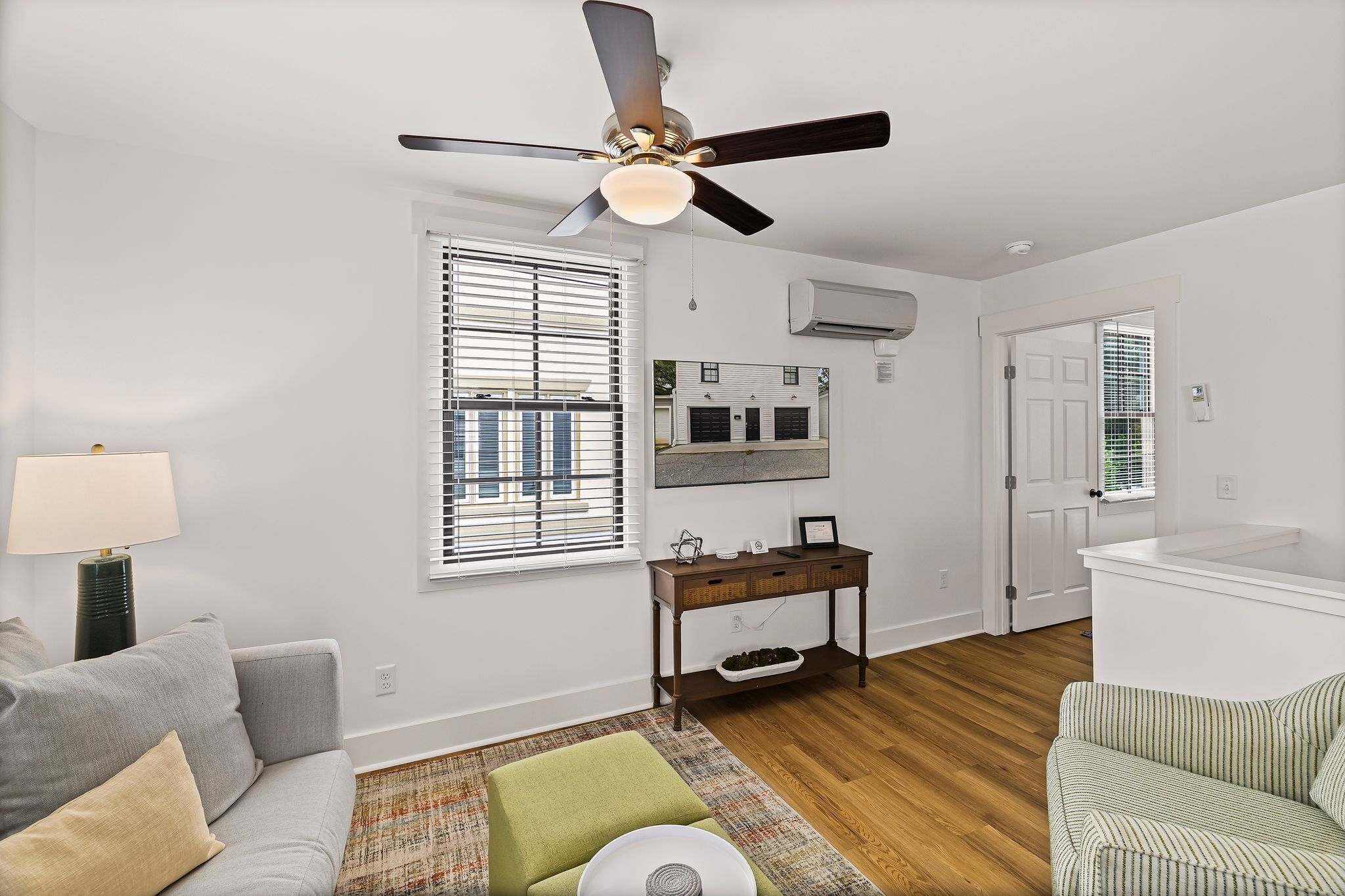 A living room with a ceiling fan, a sofa, a coffee table, a patterned rug, and a small side table.
