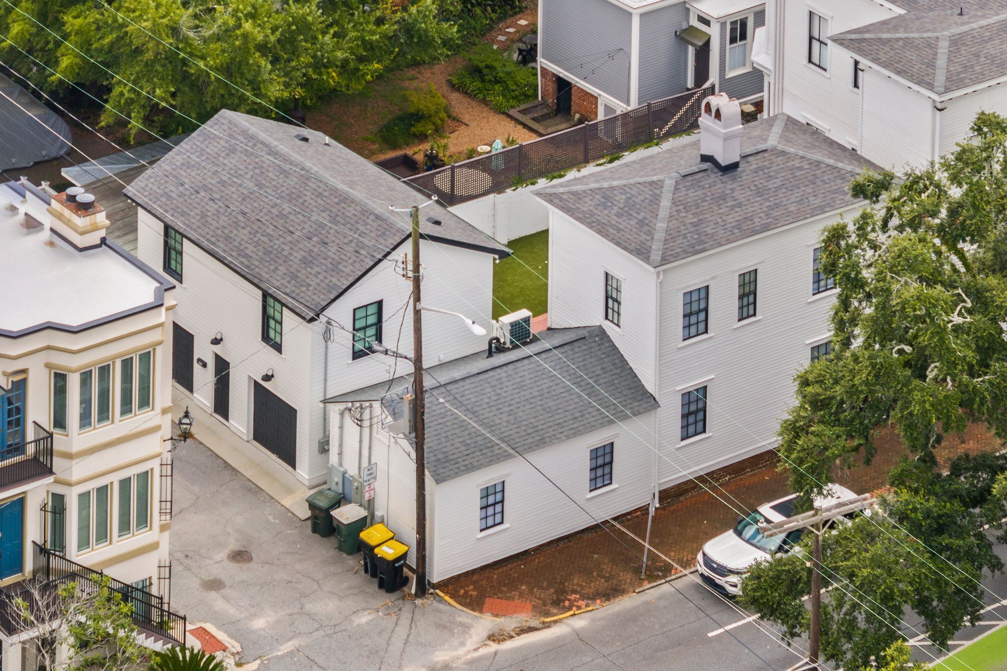 Un quartier résidentiel avec des maisons blanches, un garage bien visible et une rue où une voiture est garée.