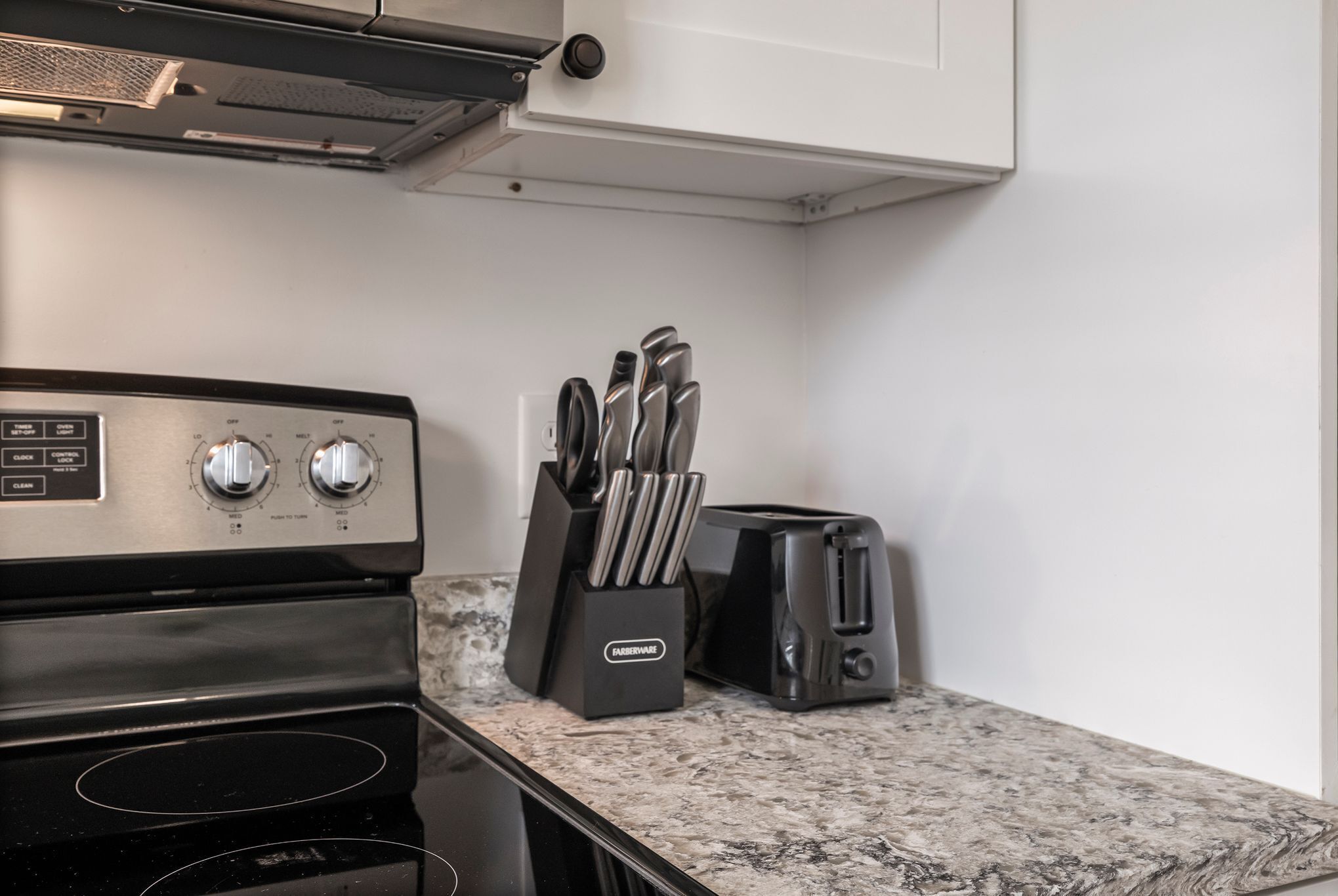 A kitchen with a stove, toaster, and knife block.