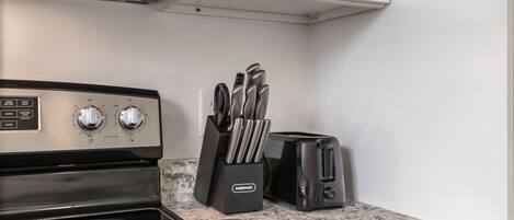 A kitchen with a stove, toaster, and knife block.