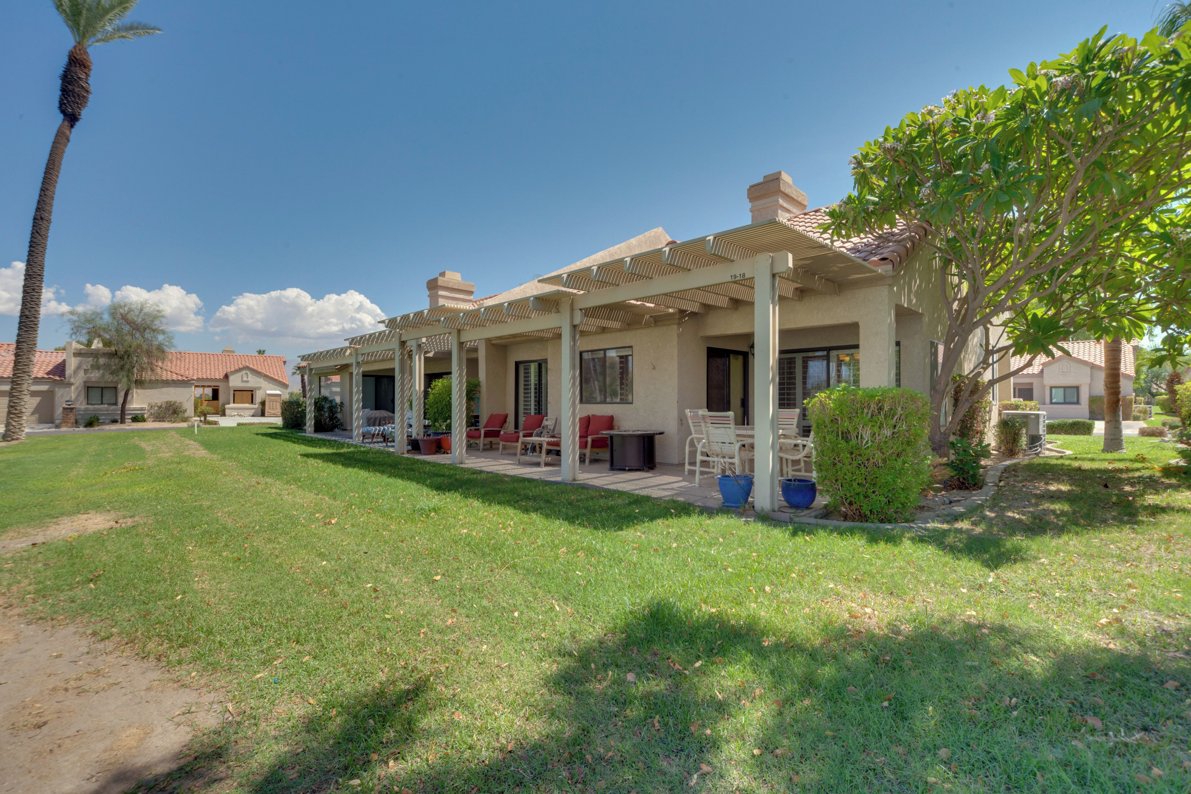 A residential property with a covered patio, outdoor seating, and a well-maintained lawn.