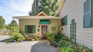 Ein Haus mit Kiesweg, einer Veranda mit Bank und verschiedenen Blumentöpfen.