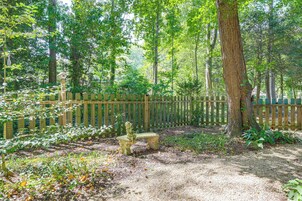 A garden with a wooden fence, a bench, and a birdhouse.