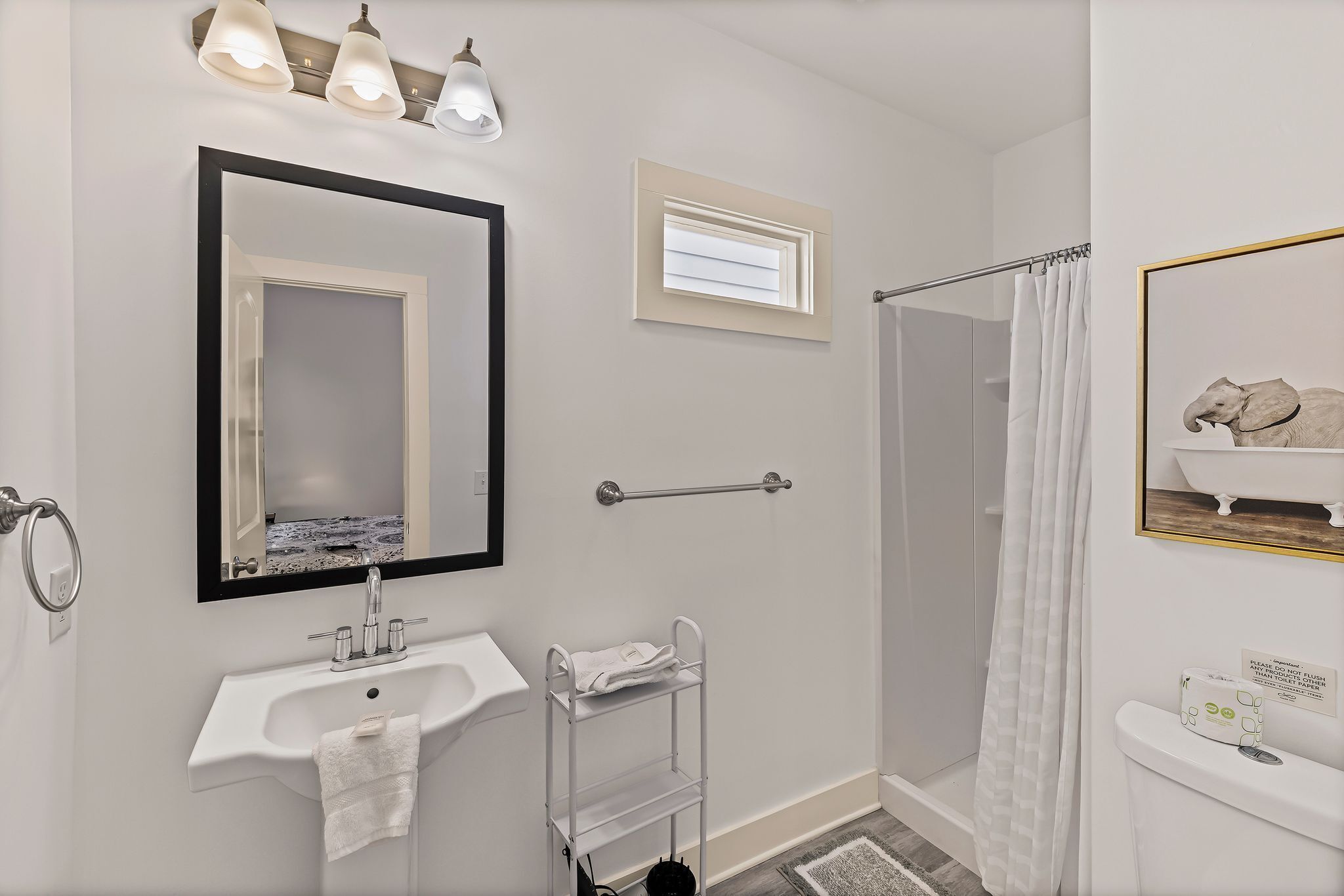 A modern bathroom with a sink, mirror, towel rack, shower, and toilet.