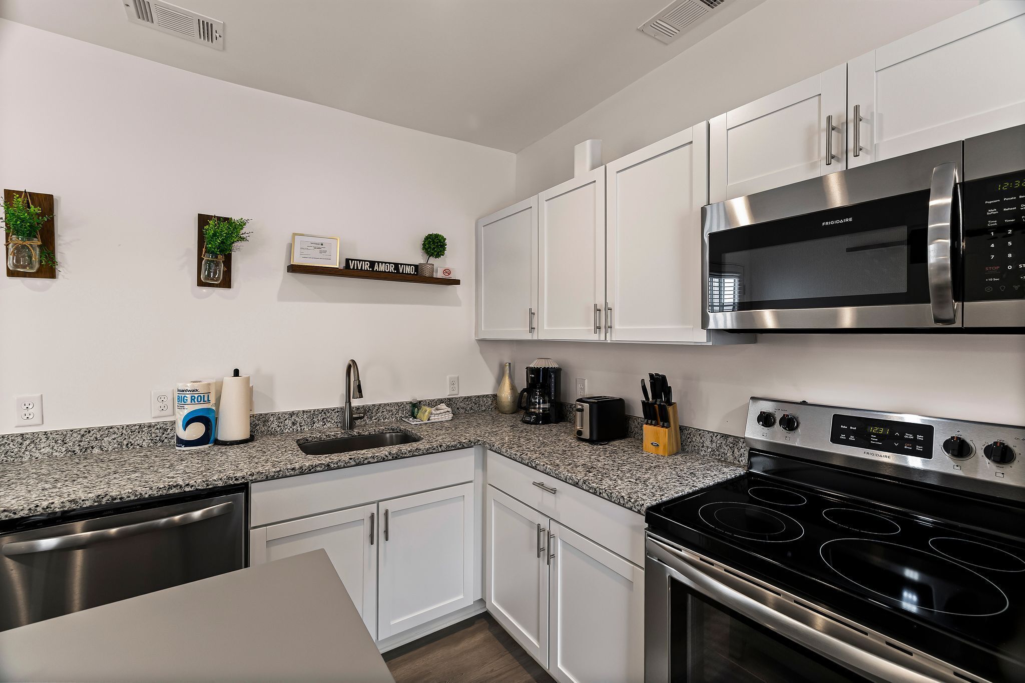 A modern kitchen with white cabinets, a stainless steel microwave, and a black stove.