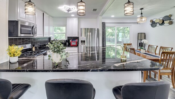 A modern kitchen with a large island, stainless steel appliances, and pendant lighting.