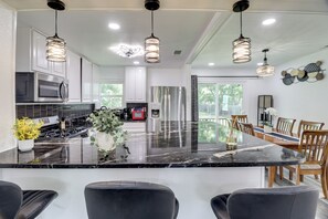 A modern kitchen with a large island, stainless steel appliances, and pendant lighting.