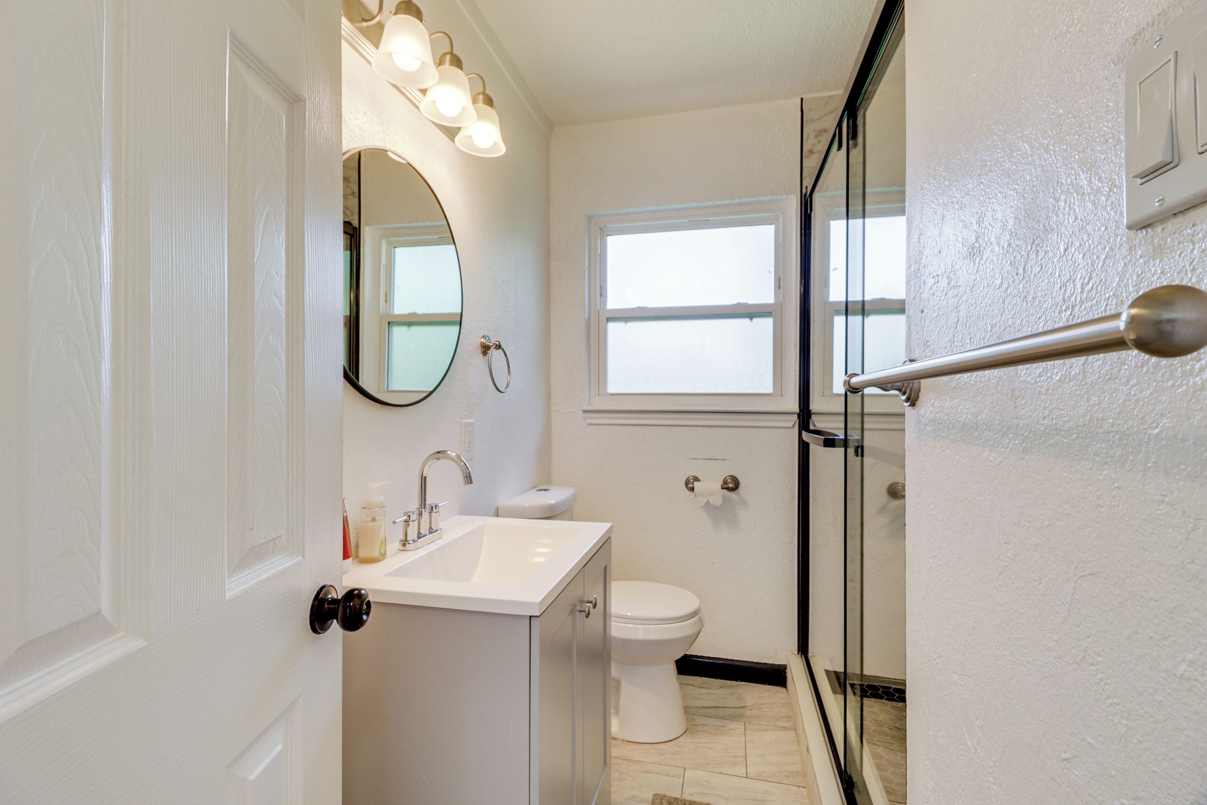 A bathroom with a white sink, mirror, and toilet.