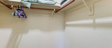 A corner of a room with a white wall, a wooden beam, and a shelf with folded clothes and a purple item.