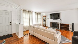 Ein Wohnzimmer mit einem weißen Sofa, einem Kamin und einem an der Wand befestigten Fernseher.