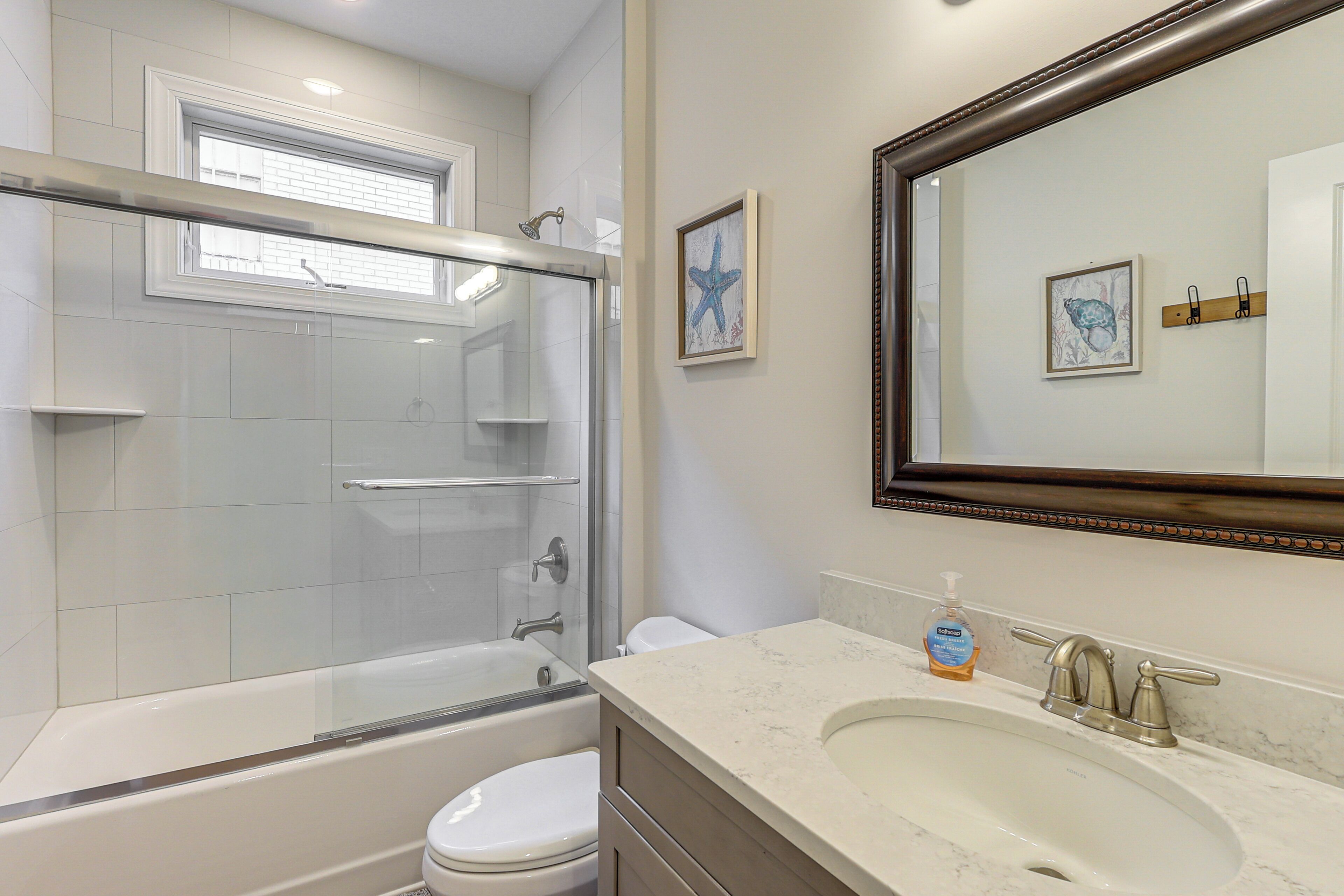 A bathroom with a glass-enclosed shower, a white toilet, a marble sink, and a large mirror.
