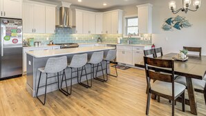 A modern kitchen with white cabinets, a stainless steel refrigerator, and a central island with bar stools.