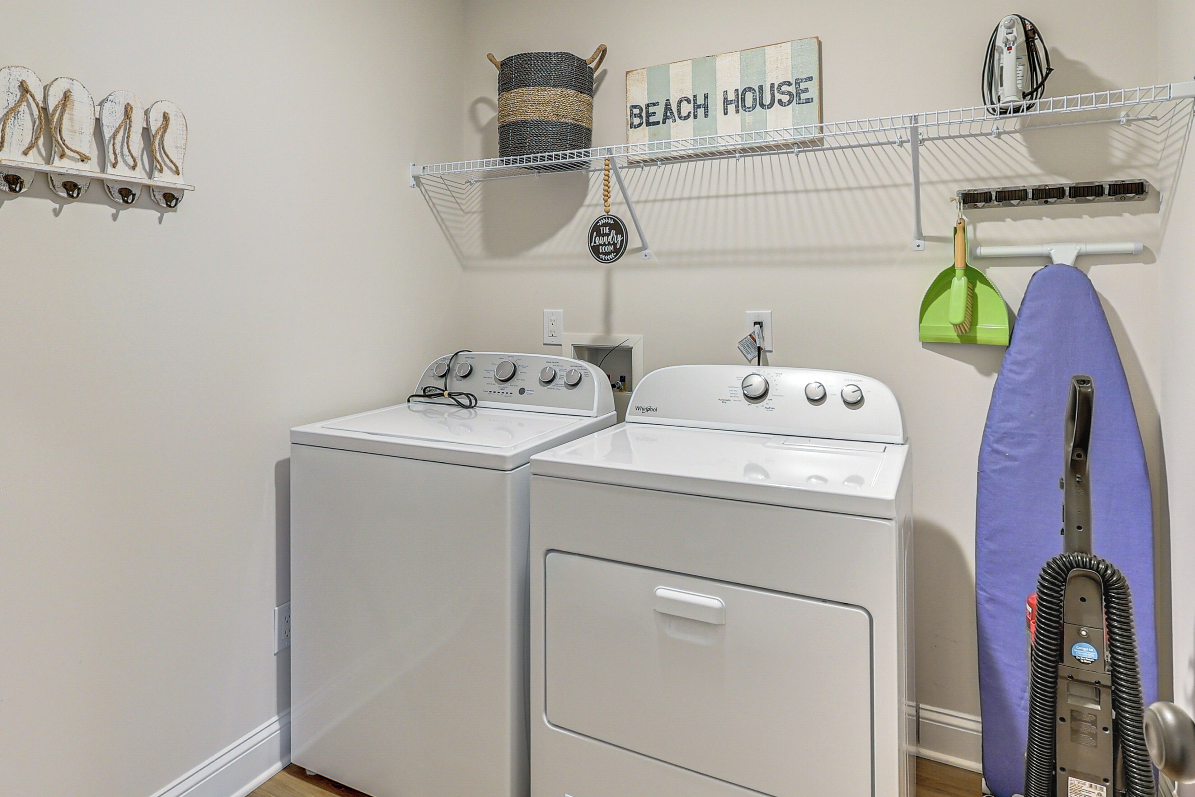 A laundry area with two washing machines, a drying rack, and a shelf with decorative items.