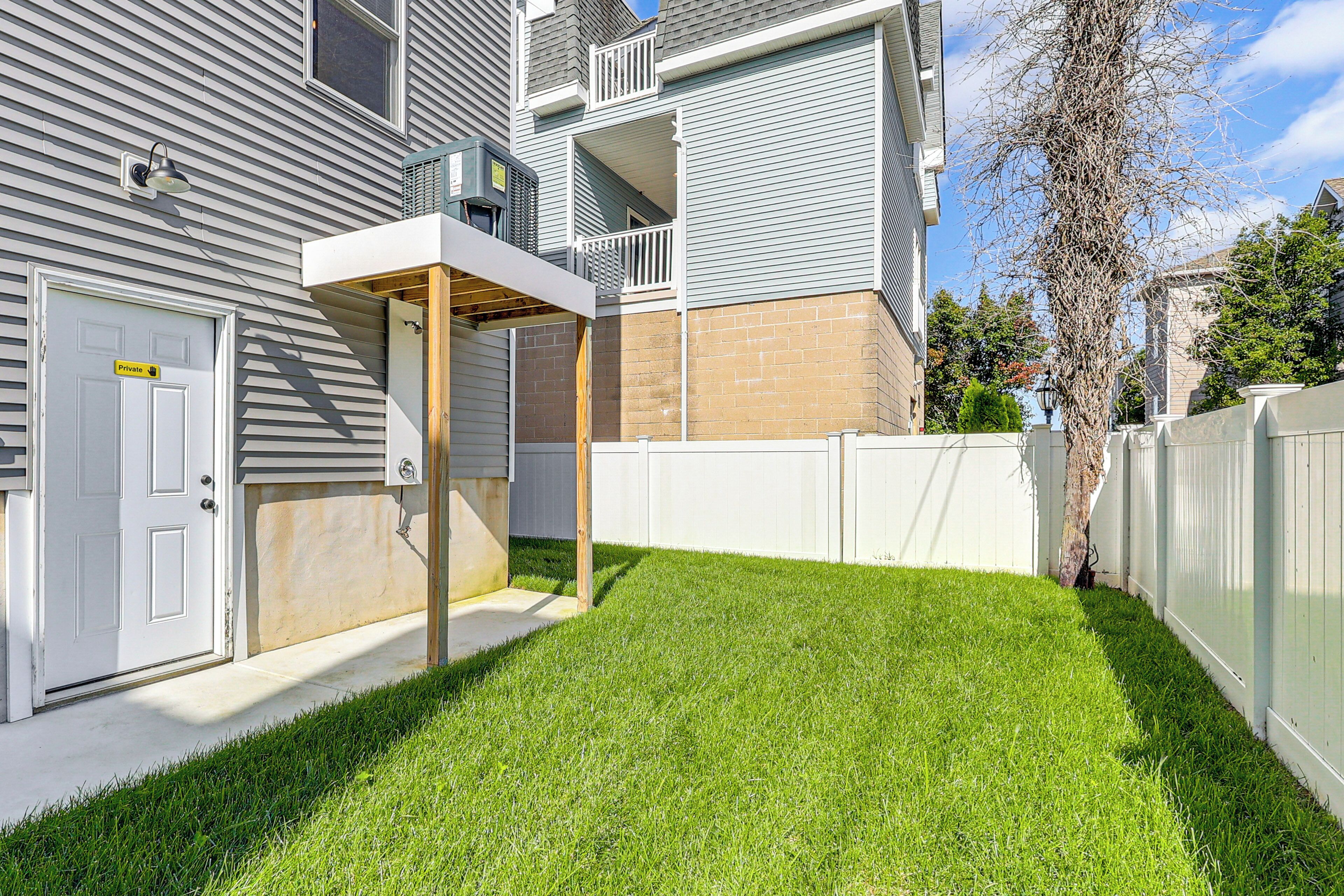 A residential property with a fenced backyard, a detached garage, and a two-story building with a balcony.