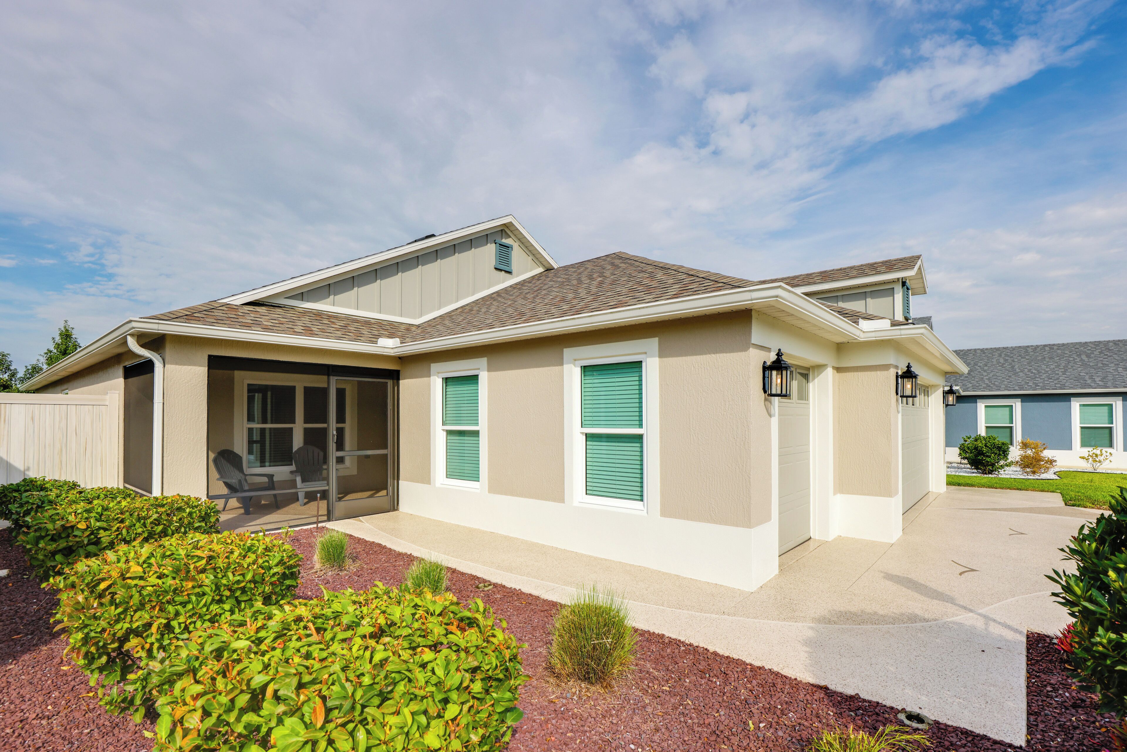 A modern two-story house with a covered patio, a garage, and a well-maintained front yard.