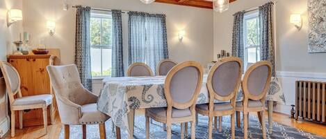 A dining area with a wooden table, six chairs, a patterned rug, and a wooden cabinet.
