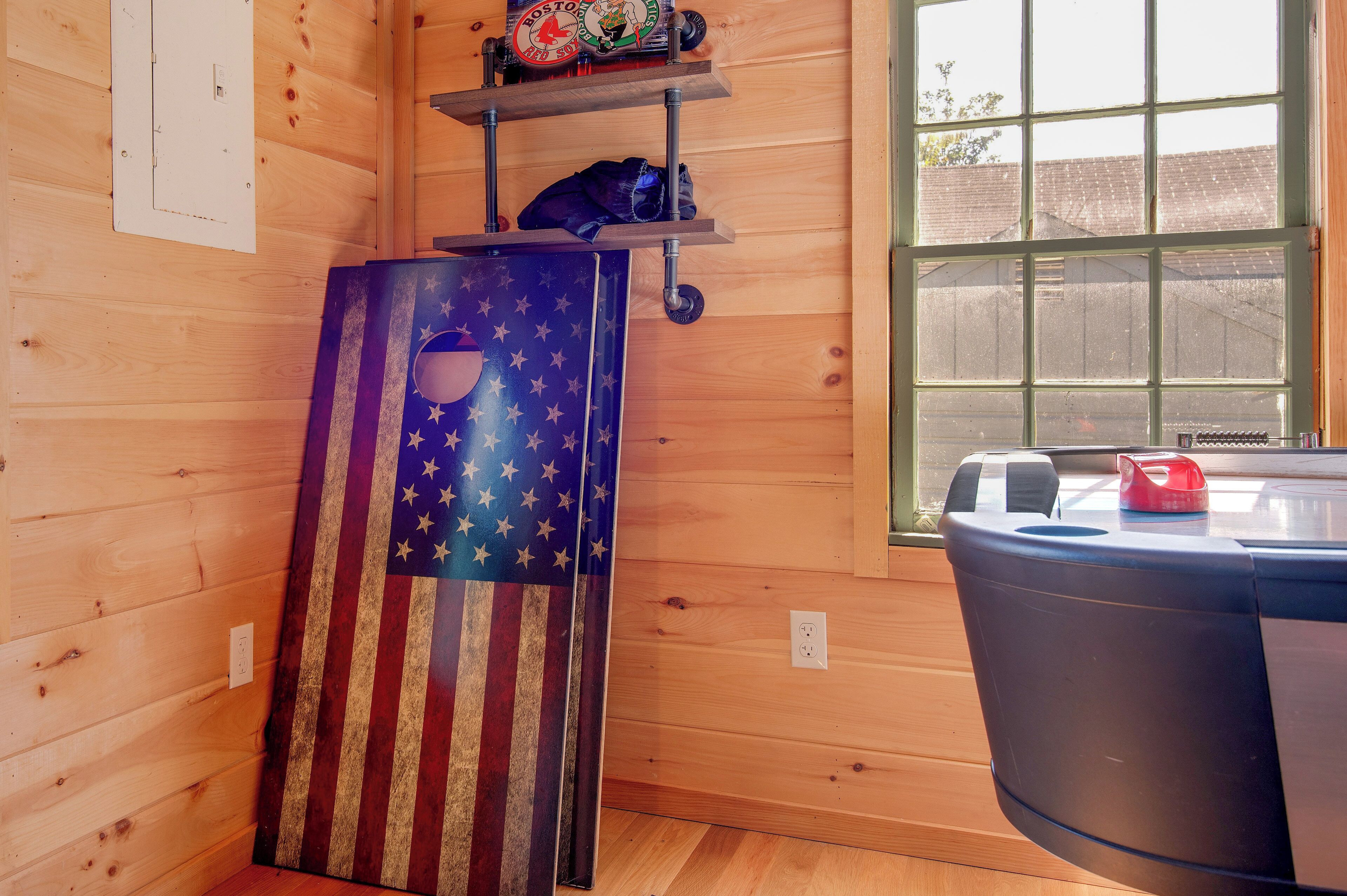 Interior de fusta amb una finestra, una estant amb una gorra dels Boston Red Sox, una porta amb temàtica de bandera i un cubell de brossa.