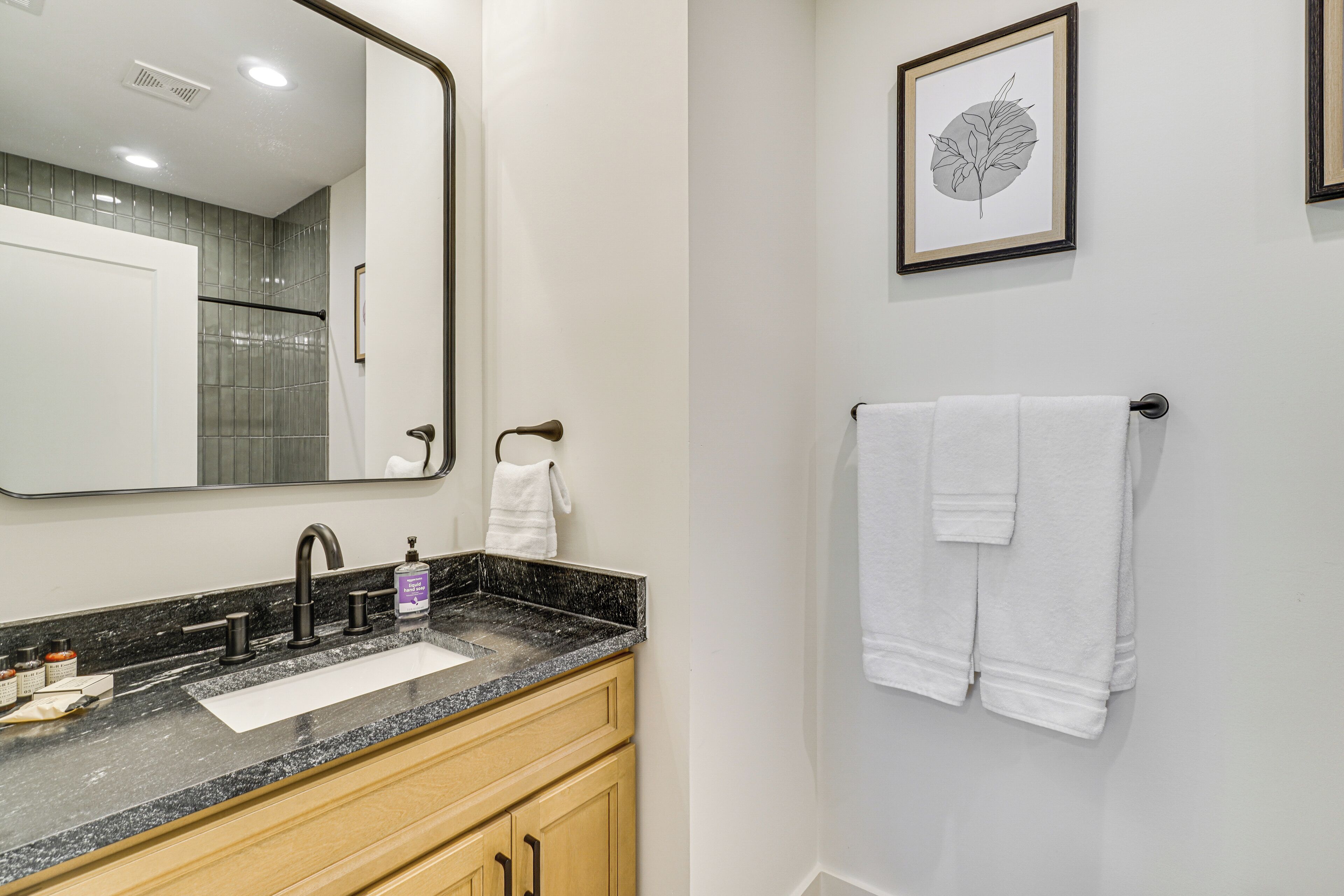 Une salle de bain avec un grand miroir, un lavabo et un porte-serviettes.