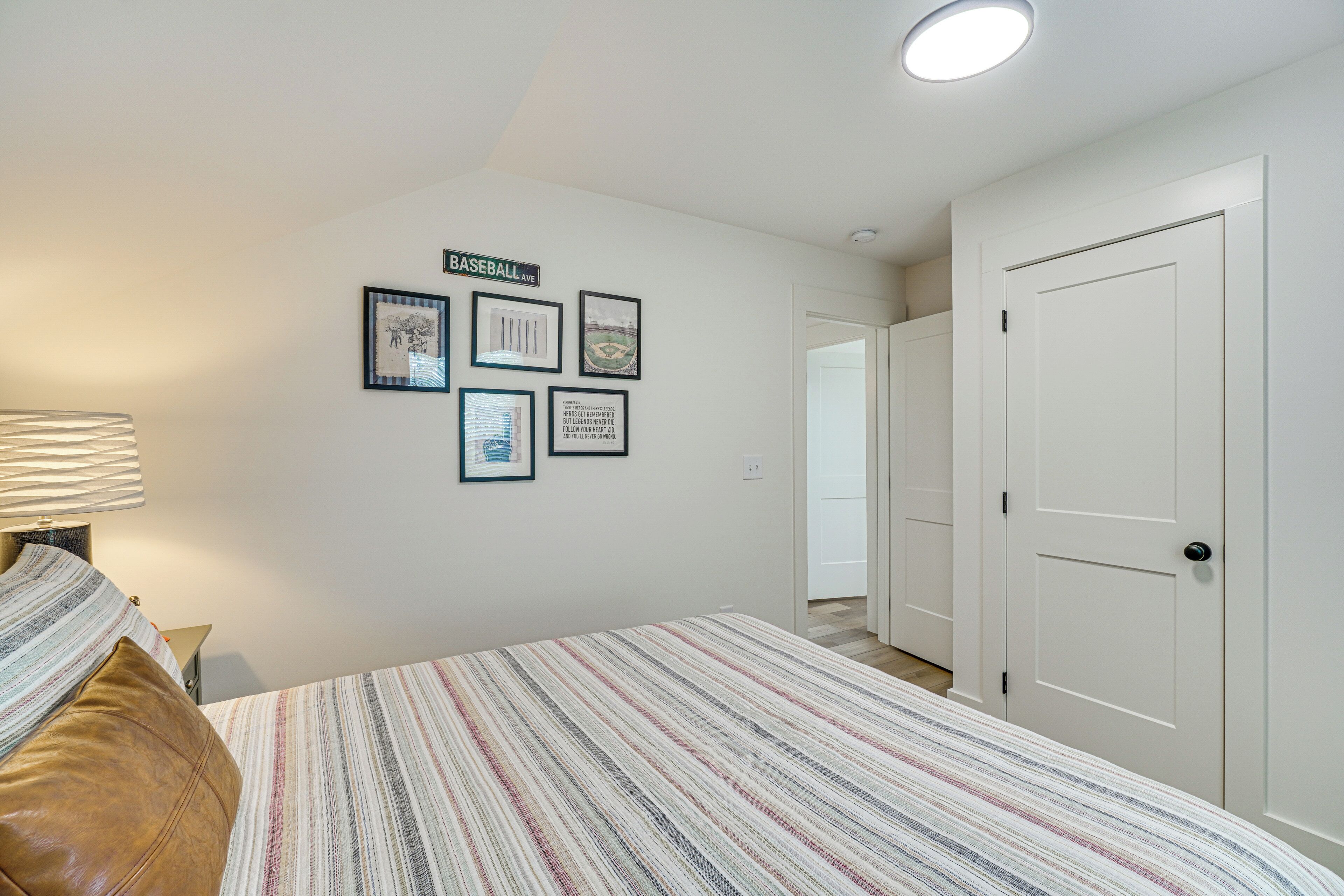 A bedroom with a bed, a nightstand, a lamp, and framed pictures on the wall.