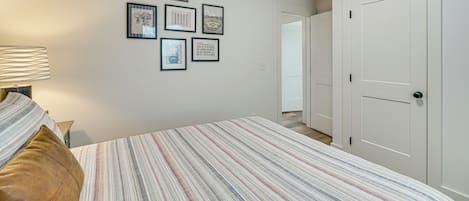 A bedroom with a bed, a nightstand, a lamp, and framed pictures on the wall.