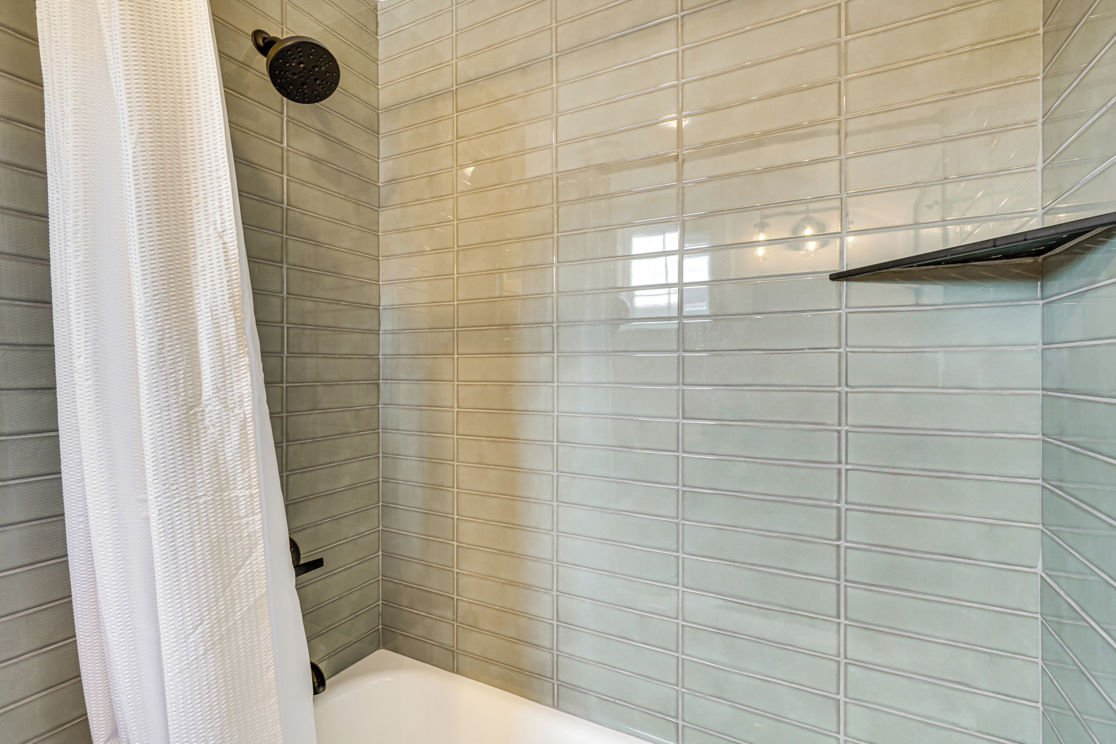 A bathroom with a shower, tiled walls, and a curtain.