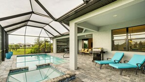 Ein überdachter Außenpool mit Liegestühlen und Grillplatz.
