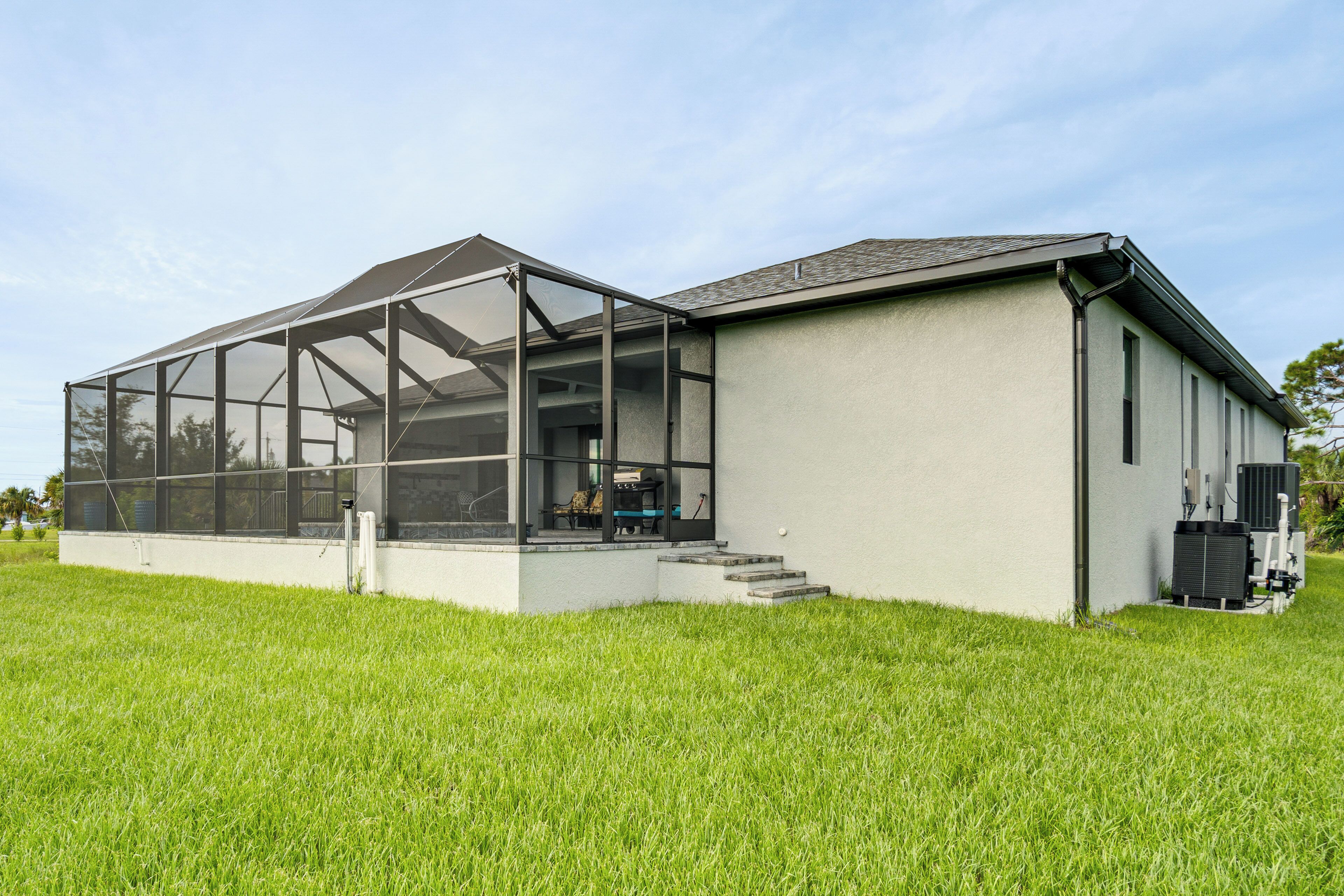 A modern building with a large glass enclosure, a flat roof, and a grassy area in front.