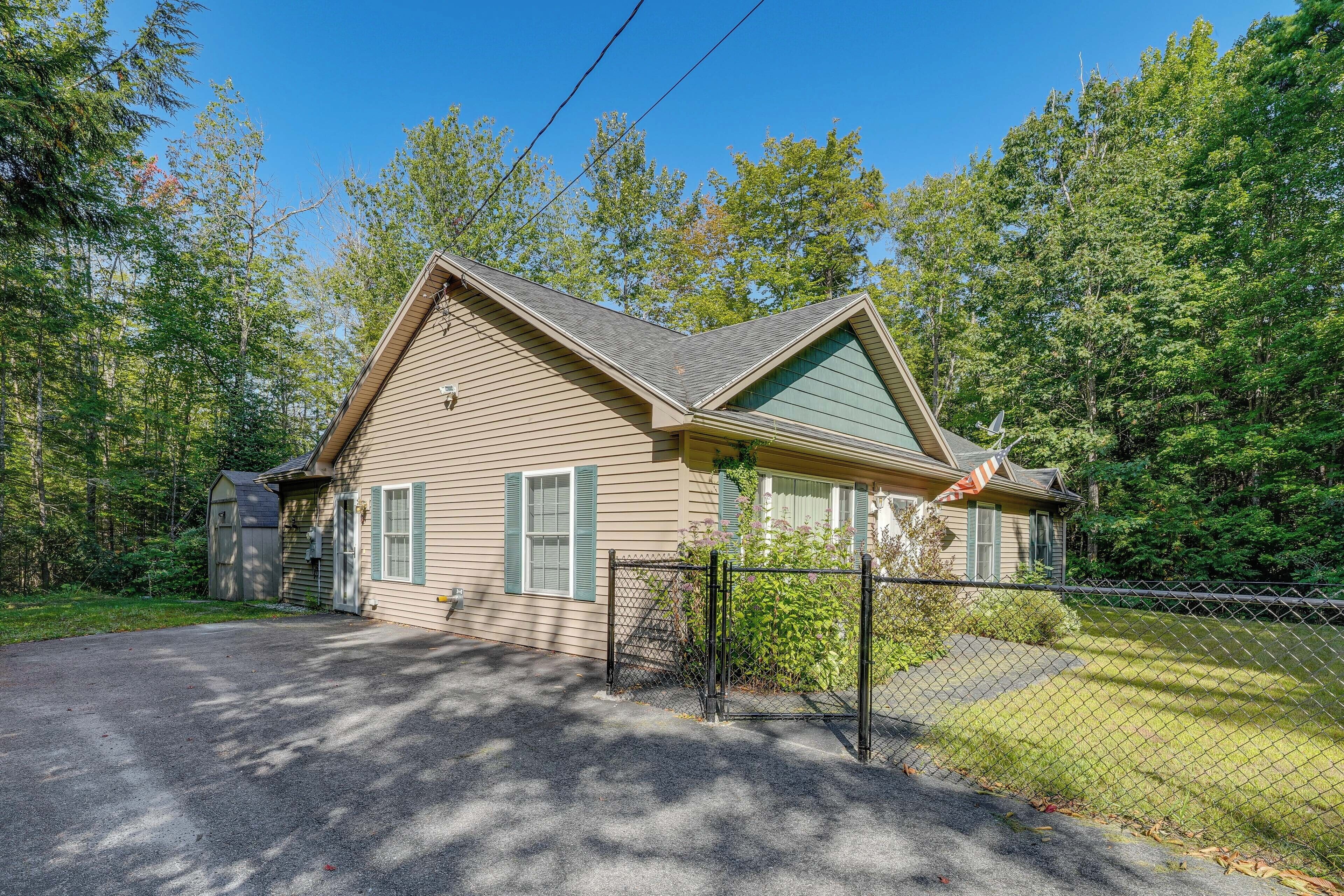 A single-story house with a sloped roof, a fenced yard, and a satellite dish.