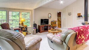 A spacious living room with leather sofas, a television, and a bookshelf. - Creekside Family Home in Cleveland: Stay & Play! (Cleveland)