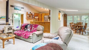 A cozy living room with a leather sofa, a glass coffee table, and a dining area with wooden chairs. - Creekside Family Home in Cleveland: Stay & Play! (Cleveland)