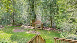 A gazebo in a forested area with a wooden deck and picnic tables. - Creekside Family Home in Cleveland: Stay & Play! (Cleveland)