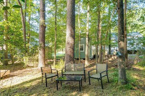 Une zone boisée avec un petit chalet et une table entourée de chaises.
