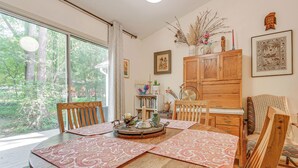 A dining area with a wooden table, chairs, and a view of trees through large windows. - Carrboro Quaint! 2 Mi to Heart of Chapel Hill! (Carrboro)