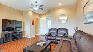 A living room with a brown leather sofa, a dark wooden coffee table, and a flat-screen TV on a black entertainment unit. - 7 Mi to Watson Lake: Prescott Valley Home w/ Patio (Prescott Valley)