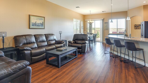 A spacious living room with a leather sofa, a coffee table, and a dining area with bar stools. - 7 Mi to Watson Lake: Prescott Valley Home w/ Patio (Prescott Valley)
